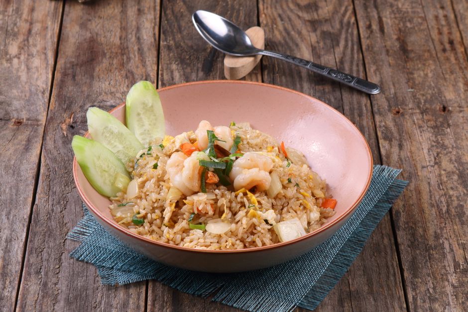 A bowl of fried rice with shrimp and green onions
