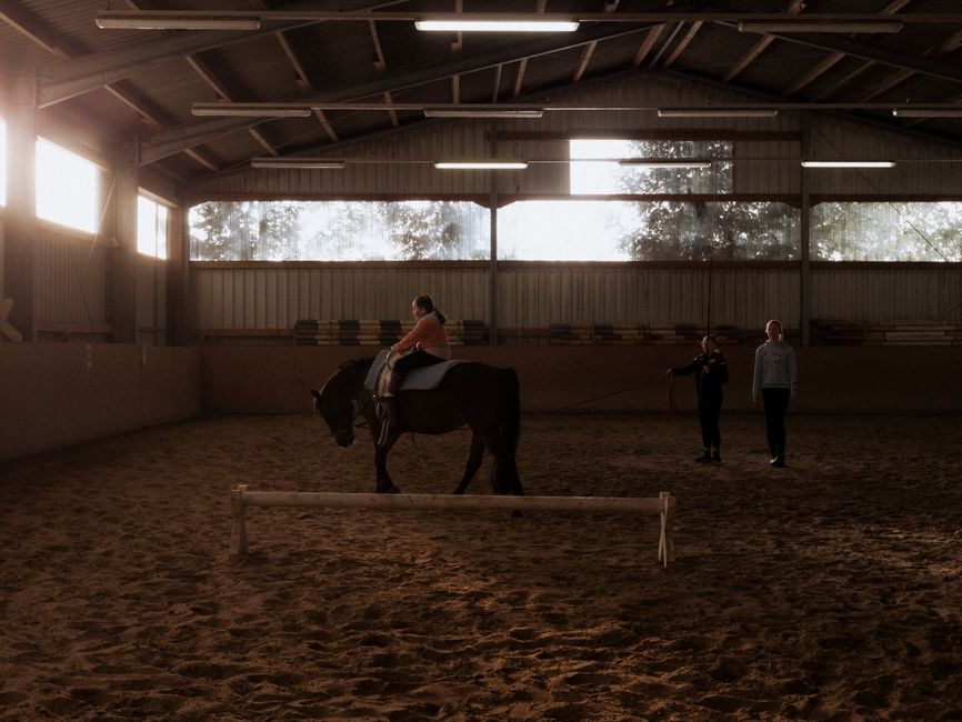 Children learning horseback riding outdoors with instructor