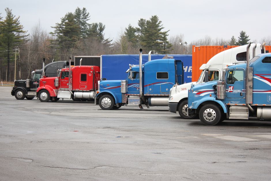 Freightliner and Kenworth tractors parked at a transport company depot