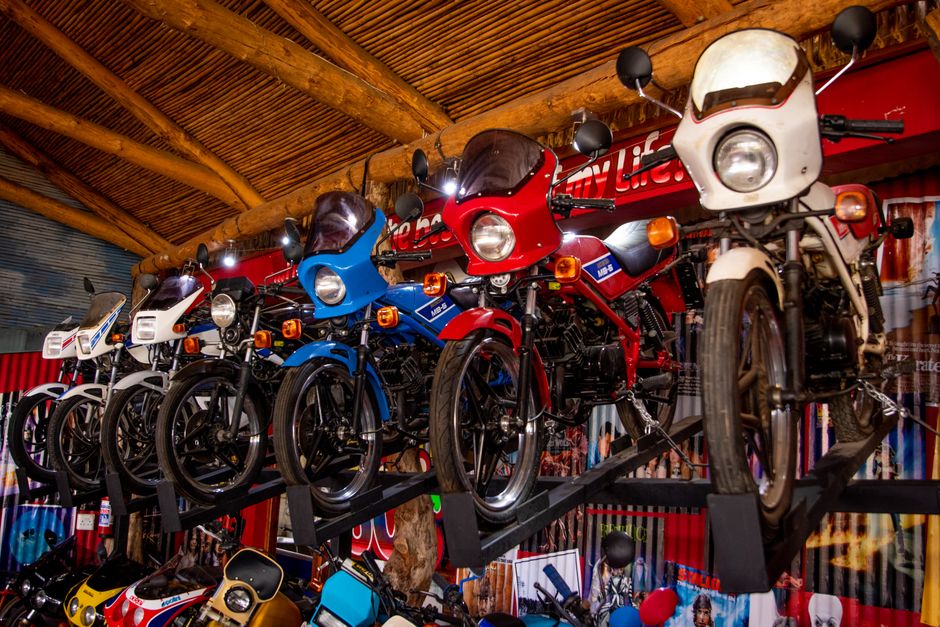 Assorted reproduction mufflers, frames, and gas tanks for vintage Indian motorcycles arranged on a worktable