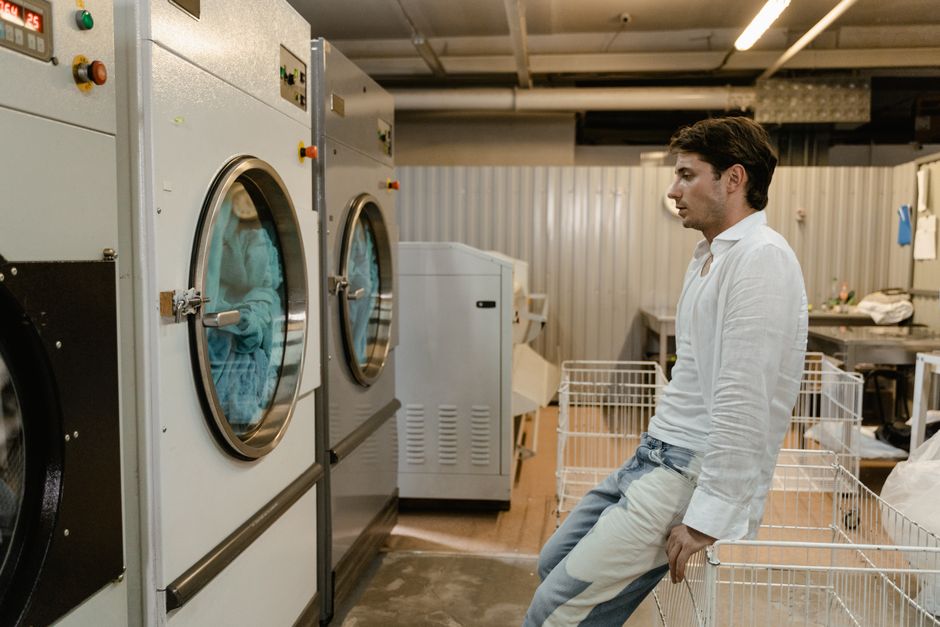 A family loading laundry into a large washing machine at a laundromat.