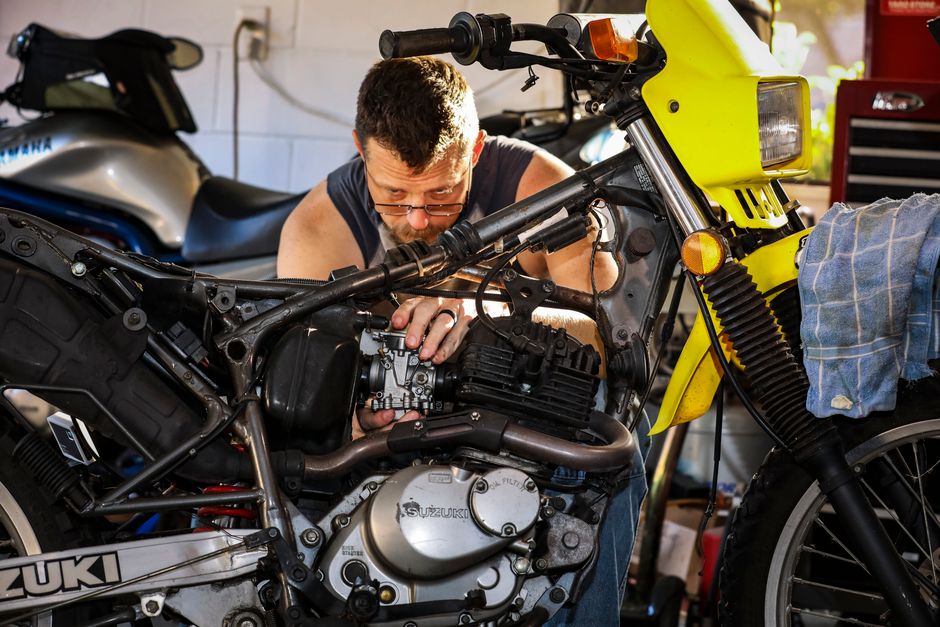 Technician tuning a motorcycle engine in a garage