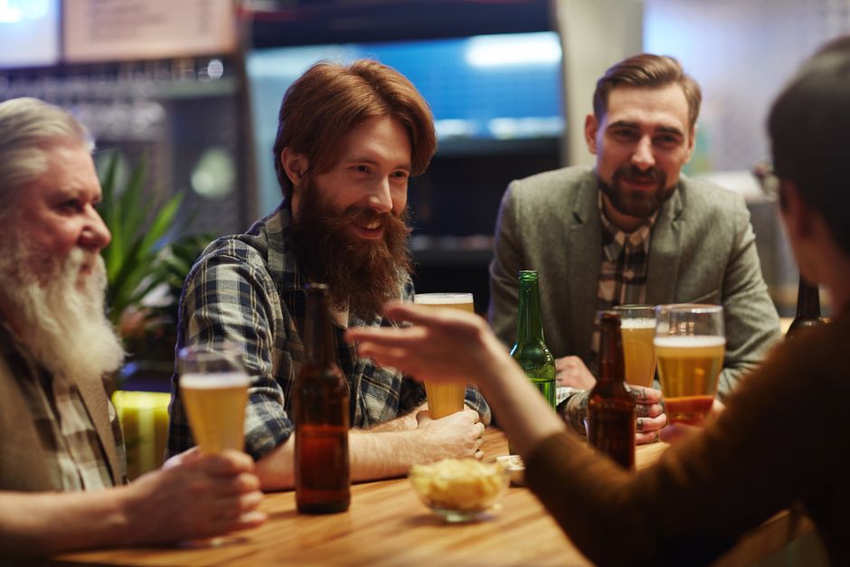 People gathered at a table enjoying burgers, grilled dishes, and drinks in a bar environment.