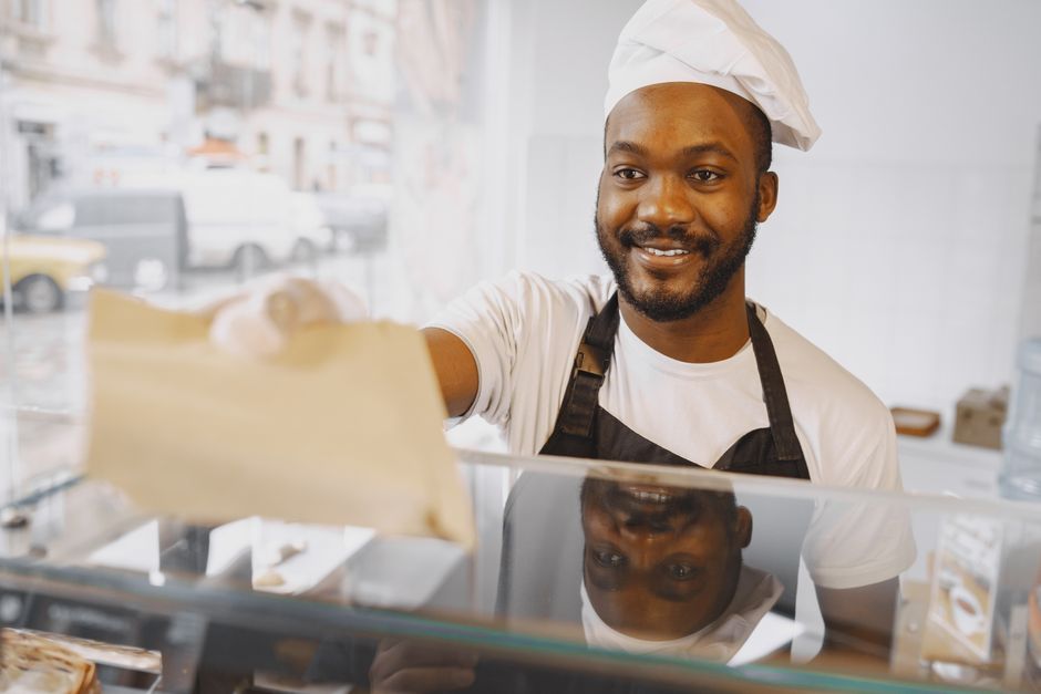 Friendly baker serving customers at a donut shop counter