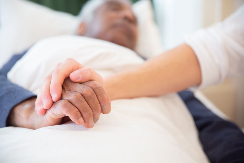 Hospice nurse providing comfort measures to elderly patient at home