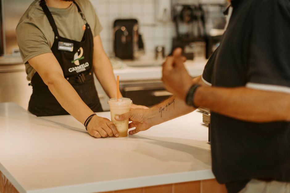 Cafe staff serving drinks and smiling customers inside a juice bar