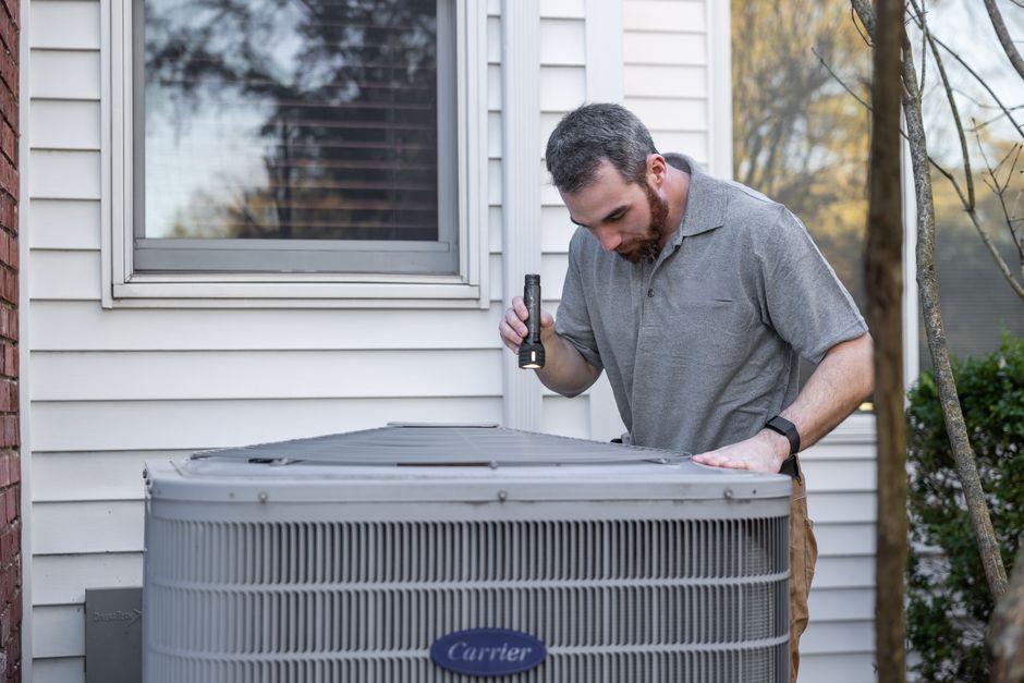 Technician servicing a heat pump outside a home