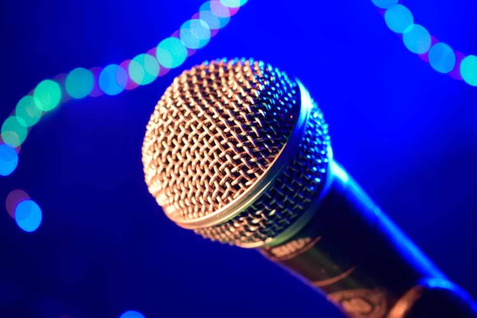 Guests singing during a karaoke night with a live band performing in the background.