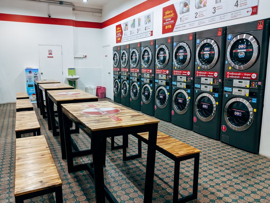 Clean and modern laundromat with washing machines and dryers in rows.