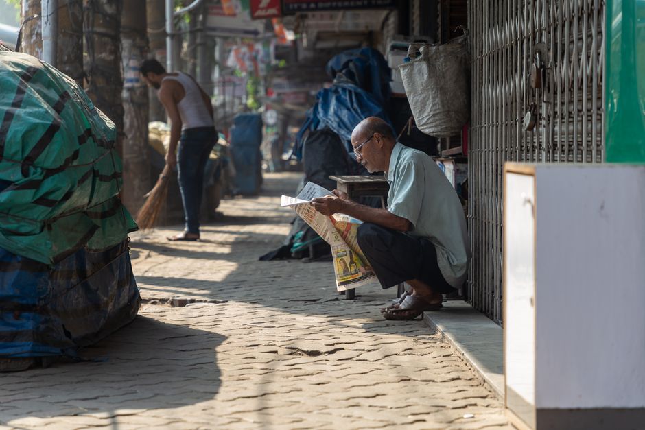 Person reading a local newspaper at a table