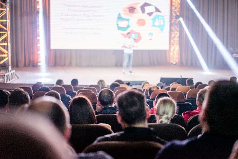Corporate conference in progress with audience and speaker on stage