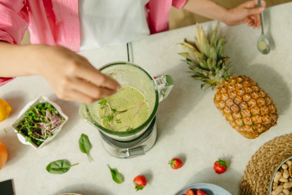 A selection of colorful smoothies being blended with fresh fruits and leafy greens