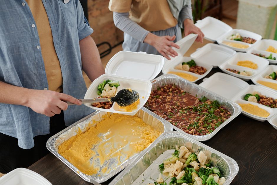 Volunteers serving hot meals to people in a community dining hall