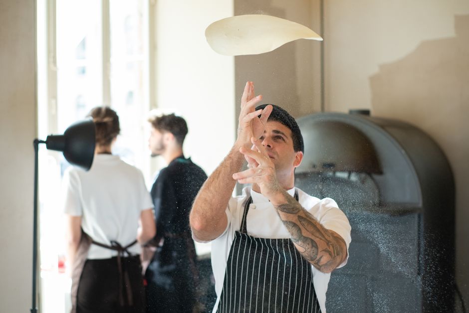 Team working together preparing pizza dough in a restaurant kitchen
