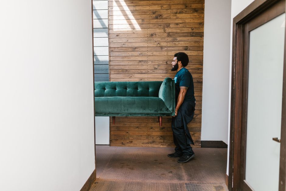 Professional movers lifting a sofa in a modern home