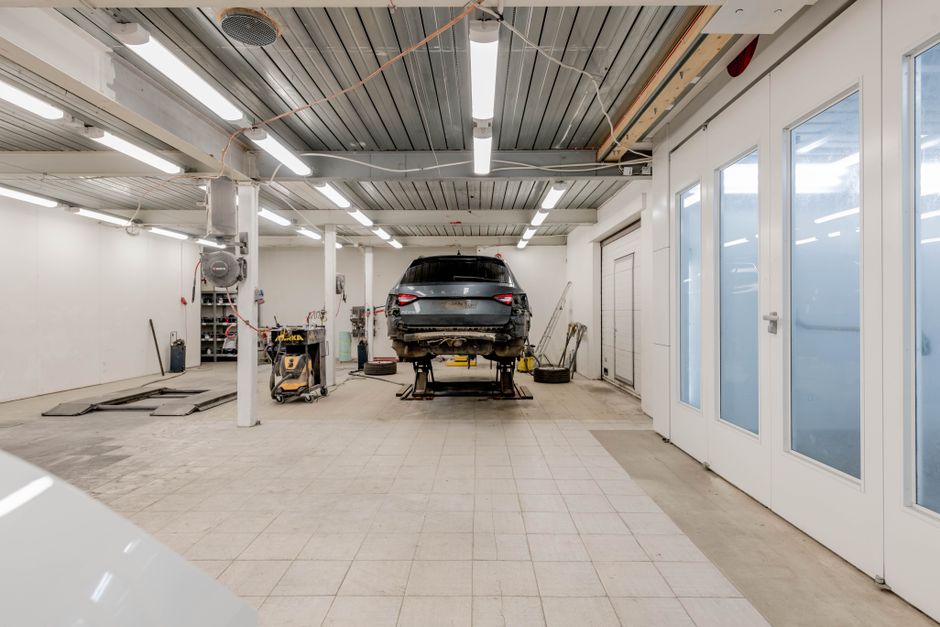 Spacious, well-equipped auto body repair shop with vehicles under restoration