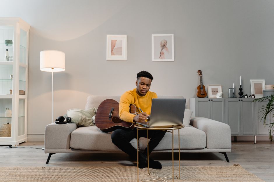 Songwriter working from home studio with acoustic guitar