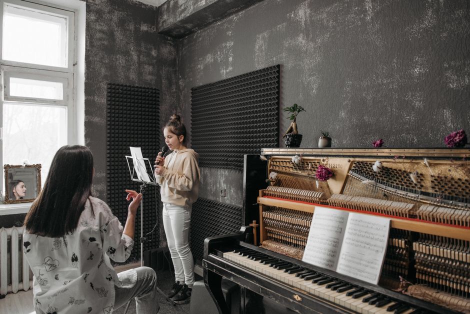 Instructor coaching a student during a vocal lesson in a recording studio