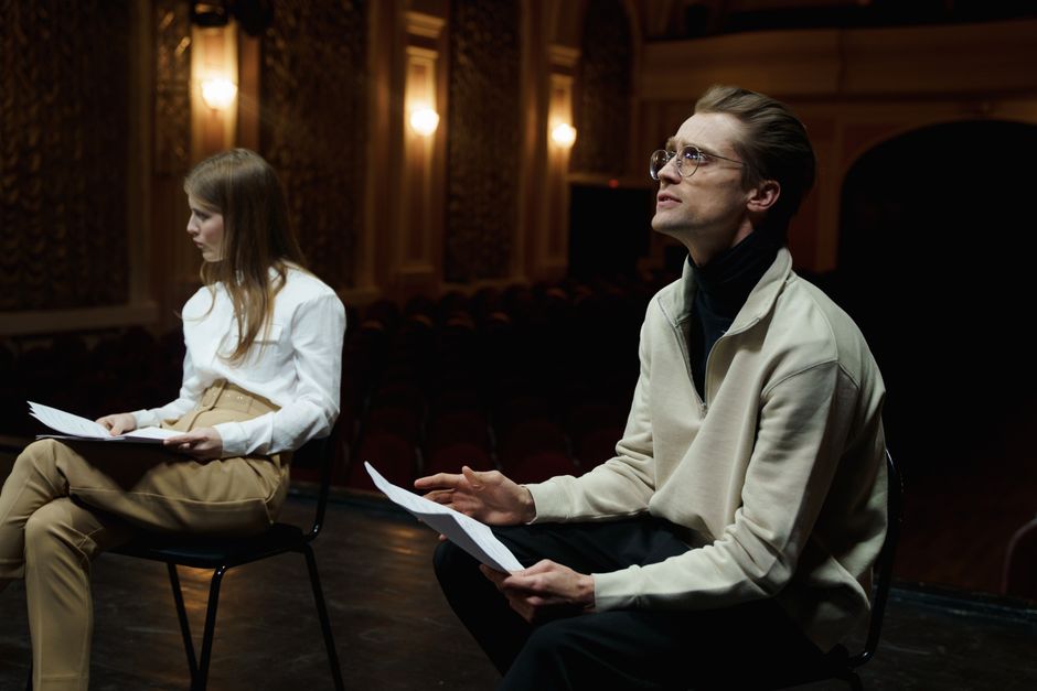 A theater rehearsal with a playwright and cast on stage.