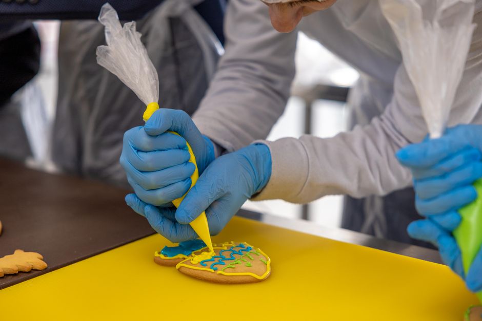 Closeup of hands piping icing in a cake decorating workshop