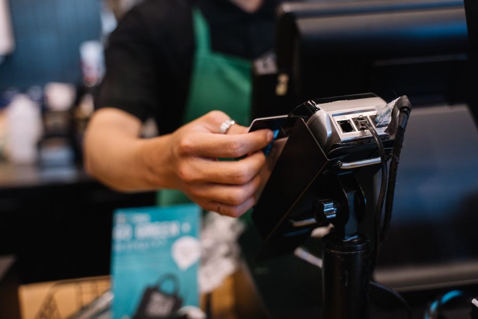 Retail cashier swiping customer credit card through payment terminal