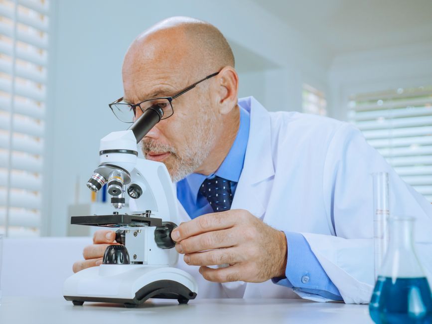 Pathologist examining histology slide under microscope