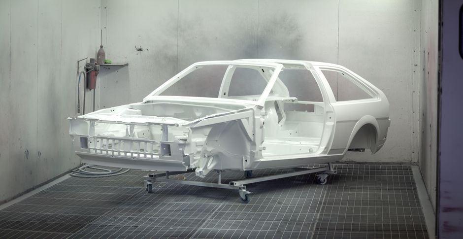Technician applying paint to vehicle in professional workshop