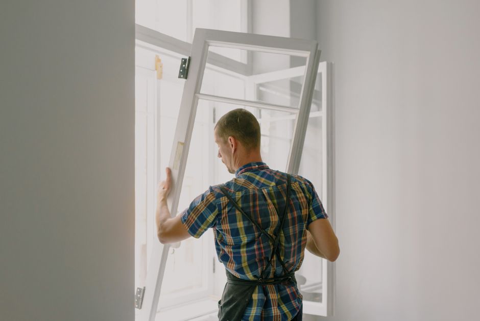 Window installation professional examining the exterior window frame of a house