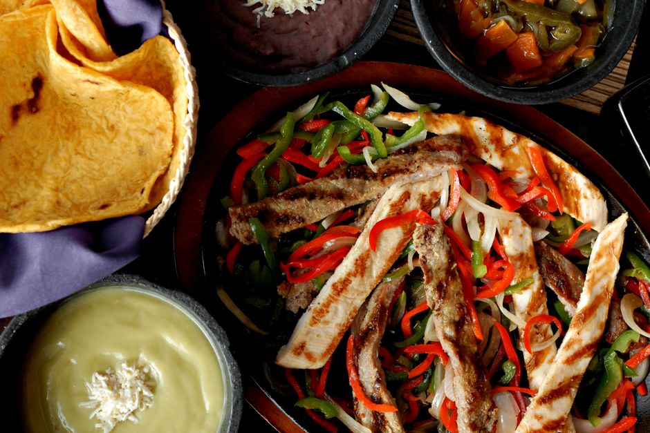 A vibrant plate featuring various Mexican-style grilled meats served with garnishes.