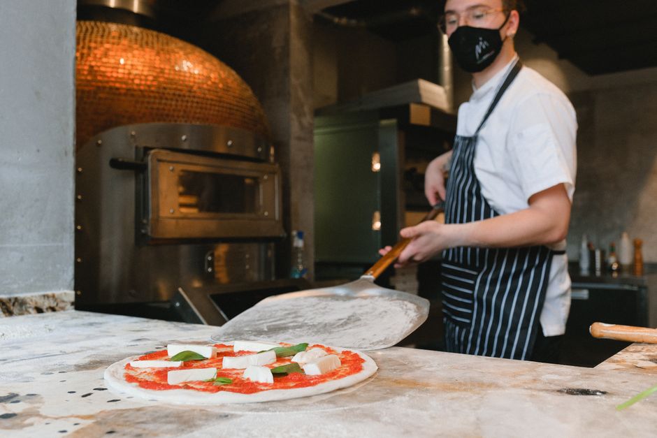 Chef preparing Neapolitan-style pizza at a wood-fired oven