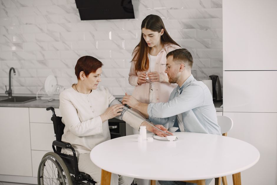 An elderly woman is assisted by a professional caregiver in a home setting