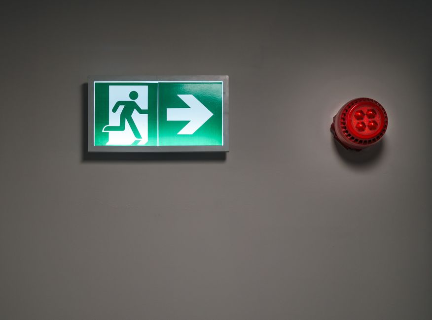 Fire alarm and emergency lighting fixtures installed in a commercial building corridor.